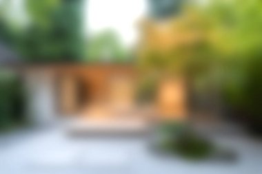 Modern mimari ve yemyeşil çevreye sahip huzurlu bir Zen bahçesinin bulanık görüntüsü, rahatlama ve meditasyon için huzurlu bir vaha yaratıyor..