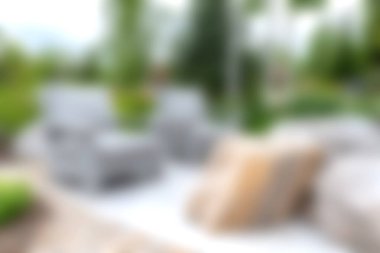 Gri sandalyeler ve yumuşak yastıklarla çevrili, yemyeşil, rahatlamak ve doğanın güzelliğinin tadını çıkarmak için mükemmel, rahat bir açık hava oturma alanı..