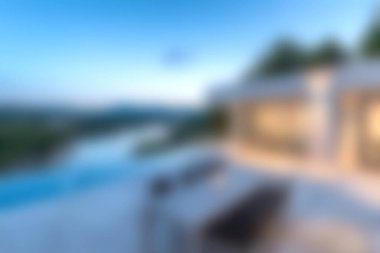 Günbatımında sakin manzaranın nefes kesici manzarasını sunan, şık bir yüzme havuzunun yer aldığı, modern bir açık hava verandasını gösteren sakin bir sahne..