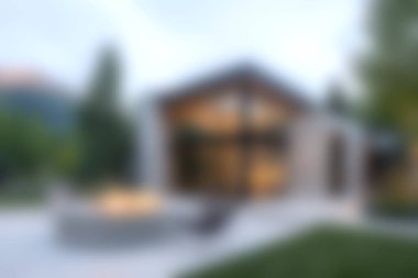 Yeşilliğe gömülü modern ev tasarımı. Geniş pencereli güzel bir dış görünüşü var. Akşam ışığı bu yerleşim yerinin sükunetini ve zarafetini vurguluyor..