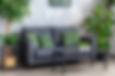 Yeşil yastıklarla bezenmiş, canlı iç mekan bitkileriyle tamamlanmış gri bir kanepenin bulunduğu rahat, modern bir oturma odası, rahatlama için şık bir atmosfer yaratıyor..