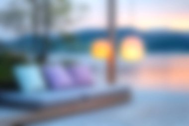 Renkli yastıkların bulunduğu rahat bir açık hava salonu, gün batımında sıcak yaz akşamlarında dinlenmek için mükemmel bir dinlenme alanı sunuyor..