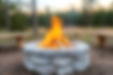 Kamp ateşi kırsal bir ateş çemberinde titreşiyor, sakin bir açık hava günbatımında sıcak ve davetkar bir atmosfer yaratıyor..