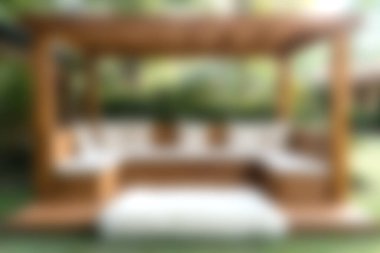 Pofuduk yastıklarla süslenmiş ahşap bir pergola içeren büyüleyici bir açık hava sahnesi, doğanın sükuneti ortasındaki rahatlama için mükemmel..