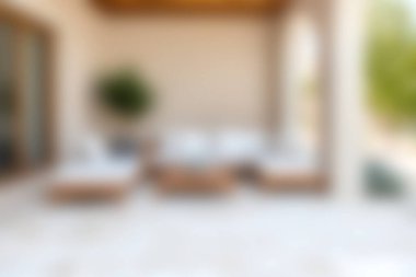 Bu resim, sakin doğal bir arkaplan karşısında rahat mobilyaların sergilendiği, rahatlamak için tasarlanmış modern bir açık hava salonu alanı sergiliyor..