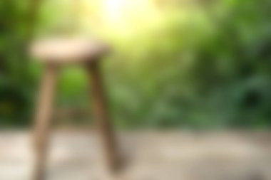 Bu görüntü, bereketli bir doğal ortamda bulunan ahşap bir tabureyi bulanık bir şekilde gösteriyor. Açık havada sükunet ve sükunet hissi uyandırıyor..