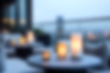 Bu görüntü, yumuşak mum ışığıyla aydınlatılmış rahat bir açık hava yemek alanını yakalar. Rahatlamak ve keyif almak için mükemmel sakin bir atmosfer yaratır..