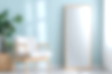 Geniş bir ayna, rahat koltuklar ve biraz yeşillik içeren sakin, modern bir iç mekan. Yumuşak renkler ve doğal ışık sakin bir atmosfer yaratır..