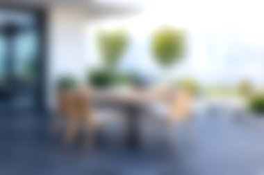 Sakin bir açık hava yemek alanında ahşap bir masa ve yemyeşil bitkilerle çevrili şık sandalyeler bulunur. Parlak atmosfer rahatlamayı ve eğlenmeyi davet eder..