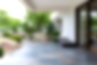 Doğal elementlerle harmanlanmış, yemyeşil ve dinlenmek ve rahatlamak için cezbedici atmosferi vurgulayan modern bir açık hava verandasının bulanık bir görüntüsü..