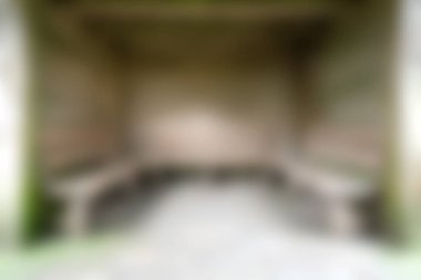 Bu görüntü, sakin, doğal bir çevreyle çevrili ahşap bankların dinlenmek için mükemmel olduğu kırsal bir açık hava oturma alanının bulanık görüntüsünü yakalar..