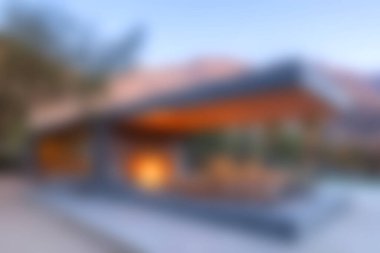 Geniş pencereli, doğayla sorunsuz bir şekilde harmanlanmış çarpıcı bir modern mimari ev. Ayarlar günbatımında sıcak renkler sergiliyor, davetkar bir atmosfer yaratıyor..