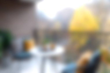 Rahat sandalyeler ve sonbahar yeşillikleriyle çevrili küçük bir masa içeren rahat bir balkon. Sıcak renkler ve sakin atmosfer huzur ve rahatlığı huzurlu bir ortama davet ediyor..