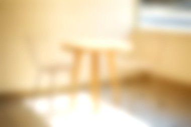 Bu görüntü, ahşap masa ve sandalyenin bulunduğu bulanık bir iç mekan yakalıyor, sıcak ve rahat bir atmosferi davet ediyor, tasarım projeleri için mükemmel..