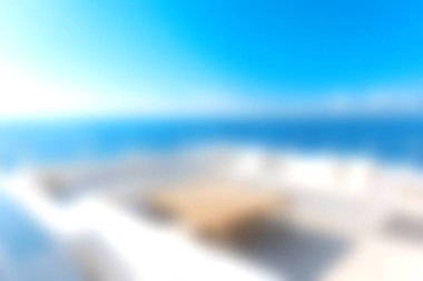 Parlak güneş ışığı altında rahat bir ahşap masa ve sandalyelerin bulunduğu lüks bir terastan çarpıcı bir okyanus manzarasıyla huzurlu bir huzur yaşayın..