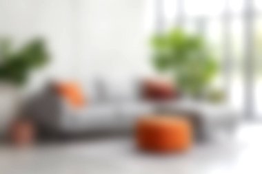 Canlı turuncu yastıklarla bezenmiş, kapalı alandaki yemyeşil bitkilerle eşleştirilmiş gri bir kanepenin olduğu şık bir oturma odası sahnesi. Mekan sıcaklığı ve rahatlığı yayarak modern ev estetiğini geliştiriyor..