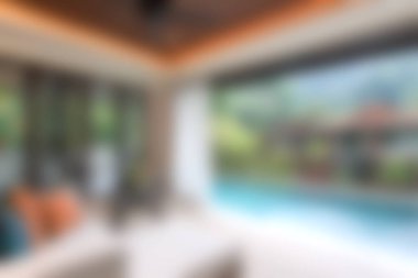 Yumuşak mobilyaları ve geniş pencereleri olan sakin, modern bir oturma odası. Rahatlamak ve rahatlamak için mükemmel manzaralı bir havuz manzarası var..