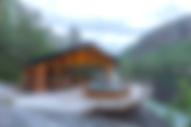 Huzurlu bir göle bakan rahat bir dağ kulübesinin güzelliğini deneyimleyin, yemyeşil ve yumuşak bulutlu bir gökyüzü, rahatlatıcı bir kaçış için mükemmel..