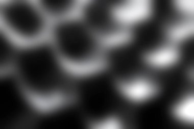 Tek renkli görüntü, çarpıcı ışık yansımaları ve gölgeler yaratan, dokuyu ve şekli vurgulayan eğri yüzeylerin soyut bir düzenini gösteriyor..