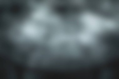 Siyah ahşap bir masa sisle kaplanarak, arka planda hafif yeşillikle sakin ve gizemli bir atmosfer yaratıyor..