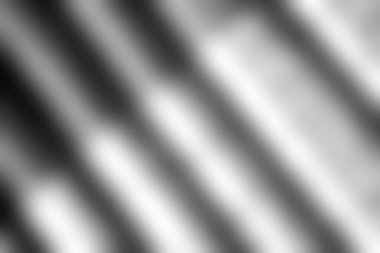 Bu resim, doğal ışık tarafından aydınlatılan, soyut ve sanatsal bir kompozisyon yaratan, dokulu bir yüzey üzerindeki siyah ve beyaz çizgilerin ve gölgelerin bir oyunudur..