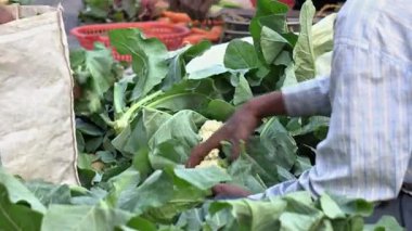 Bir adam sebze pazarında karnabahar satıyor..