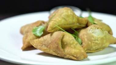 Doldurulmuş Hint samosası beyaz tabakta servis ediliyor..