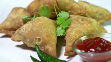 Hint samosaları (Hint üçgen pastası) beyaz bir tabakta döner. Hint geleneksel yemekleri.