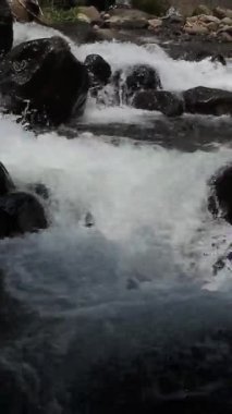 Temiz nehir suyu, doğal kayaların ve taşların üzerinden sorunsuzca akıyor..