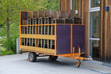 Bina girişine yakın bir konser salonu için sandalyeli endüstriyel taşıma arabasının yan görüntüsü. Lojistik ve ikmal konsepti, açık hava sahnesi. Bavyera, Almanya.