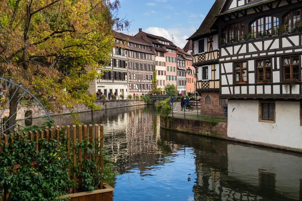 Bir nehir bir sürü binası olan bir kasabadan geçer. Su sakin ve ağaçlar yeşil. 10/15/2025