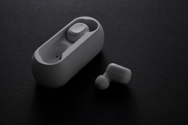 Kablosuz kulaklıkların modern fotoğrafı ve siyah yüzey üzerindeki açık kutuları taşınabilir ses teknolojisi yaşam tarzını ve minimalist temiz ürün sunumunu gösteriyor.