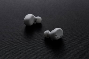 Koyu arkaplanda iki beyaz kablosuz kulaklığın stüdyo görüntüsü minimum temiz tasarım modern ses aygıtı konsepti ve kişisel teknoloji yeniliği gösteriyor..