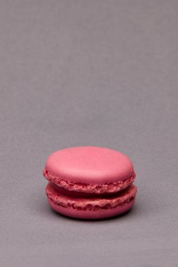 Tarafsız gri arka plana yerleştirilmiş pembe bir badem kurabiyesinin dikey görüntüsü. Tasarım veya metin yerleştirme için kopyalama alanı olan zarif asgari yiyecek fotoğrafçılığı.