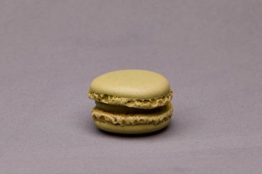 Tarafsız gri arkaplana yerleştirilmiş tek yeşil badem kurabiyesinin minimalist fotoğrafı. Fotokopi alanı olan temiz stüdyo yemekleri..