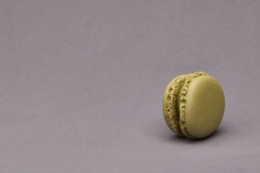 Stüdyo ışıklarıyla gri yüzeye yerleştirilmiş tek yeşil badem kurabiyesinin yatay yakın çekimi. Minimum ve zarif yemek fotoğrafı..