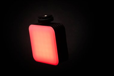 Pürüzsüz kırmızı bir LED ışık paneli, parlak yüzeyi olan siyah bir arkaplanda fotoğraflandı. Resim, görüntü ve görüntü aydınlatma için ideal dikdörtgen tasarımını vurgular.