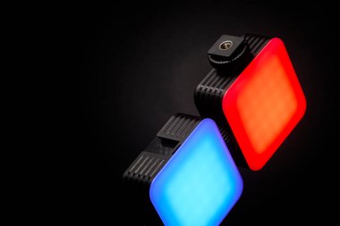 Koyu arkaplanda kırmızı ve mavi parlayan iki LED ışık paneli. Stüdyo görüntüsü onların canlı renklerini ve dikdörtgen biçimlerini yakalıyor. Fotoğraf ışıklandırma ekipmanları sunumları için ideal..