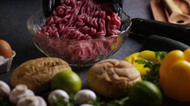 Mantar, kireç, çörek, maydanoz ve yumurtalarla çevrili kristal bir kasede kıymalı eti gösteren bir sürgülü kamera videosu..
