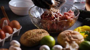 Bir kayan kamera videosu şefin elleri etrafında limon, çörek, maydanoz ve yumurtalarla kıyılmış et parçalarını öğütürken görülüyor..