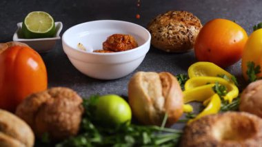 Bir kayan kamera videosu, bir şefin taze malzemelerin arasına yerleştirilmiş beyaz bir kaseye köfte servis ettiğini gösteriyor..