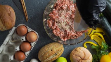 Şefin ellerinin limon, çörek, yumurta, kabak ve sarımsakla çevrili kristal bir kasede baharatla karıştırılmış kıymaya pirinç eklediğini gösteren yassı bir video..