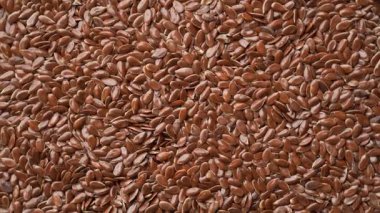 Düz açılı makro döngü videosu bej rengi susam tohumlarının çerçeve dokusunu bile doldurduğunu gösteriyor. Metin veya tasarım için yumuşak ışıklandırma ve boşluk ile temiz organik gıda arka planı.