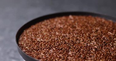 Makro, kayma bulanıklığıyla yavaşça dönen susam tohumlarını gösteren videoyu kapat. Bej renkler ve sığ odak doğal besin dokusu ve temiz organik arkaplan oluşturur.