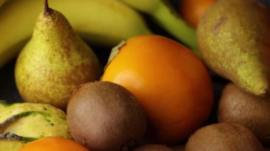 Yakın kayan bir video armut kivi hurma muz ve mandalinaları yumuşak ılık ışıklandırma ve pürüzsüz ve dokulu yüzeylerin karışımı ile birlikte düzenlenmiş..