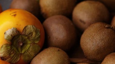 Ortasında kivi olan yoğun bir meyve kompozisyonu ve kamera sahne boyunca kayarken armut, mandalina ve balkabağı ortaya çıkıyor..