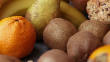 Yumuşak, sıcak bir aydınlatma ile ahşap bir tabağa yerleştirilmiş kivi mandalinalı ve maydanozlu meyveli pasta parçalarını gösteren yakın çekim bir video..