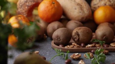 Bir sürgülü video kivi yeşil ceviz armut mandalina hamur çörekleri ve maydanozu ahşap bir yüzeye karıştırıp sıcak bir kırsal düzende yakalıyor..