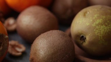 Armut, kivi, hamur işi, fındık ve maydanozu ahşap bir yüzeye yakın konulmuş sıcak doğal ışıkta gösteren dar bir yakın plan..