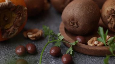 Yakın sürgülü detay videosu kivi yeşili ceviz armut mandalina hamur işi ve fındık parçalarını ahşap bir tabakta sıcak ışık altında sergiliyor..